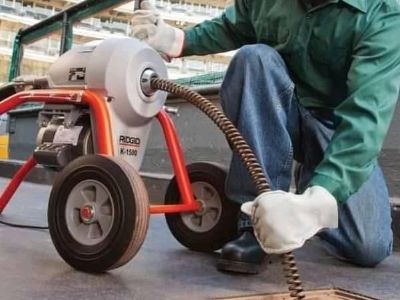 Técnico de Plomeros y Desazolve operando sonda eléctrica para el desazolve de coladera de piso